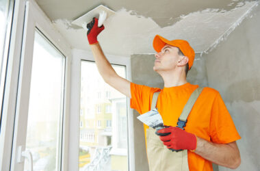 Plasterer at indoor ceiling renovation decoration with float and plaster